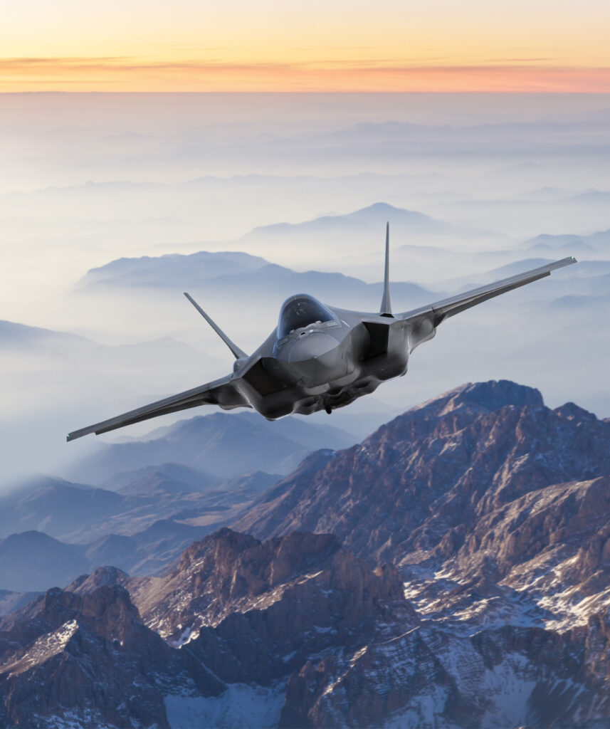 Fighter Jet flying over mountains at sunset